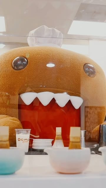 Domo chef mascot behind the cafe counter with bowls and a matcha whisk