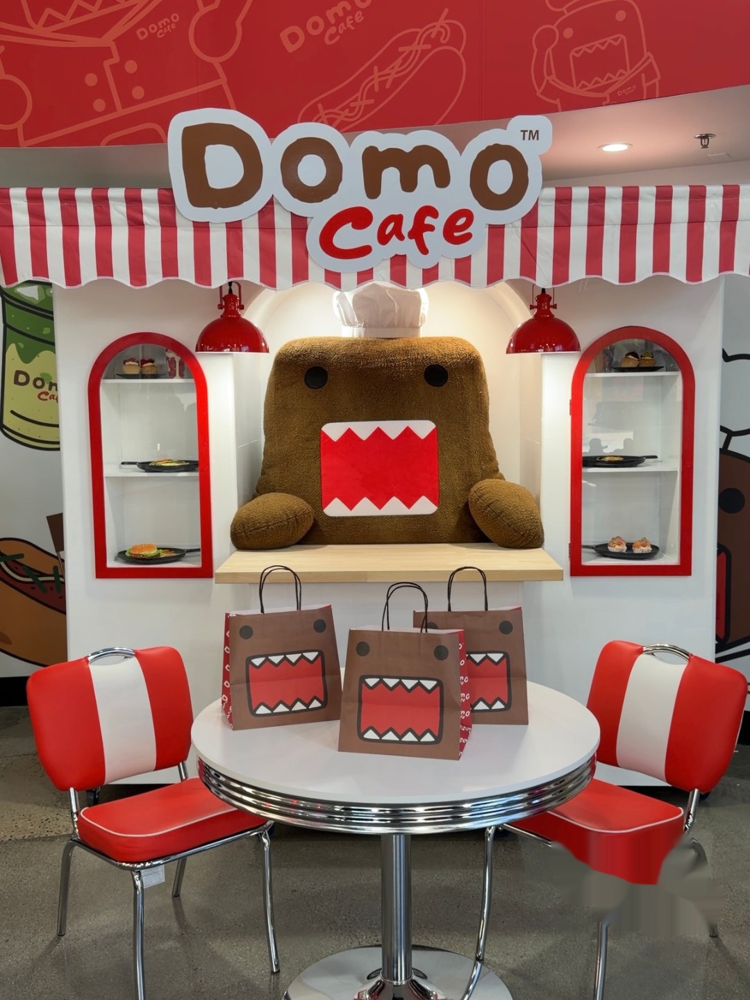Domo Cafe photo-op table with mascot, shopping bags, and diner chairs